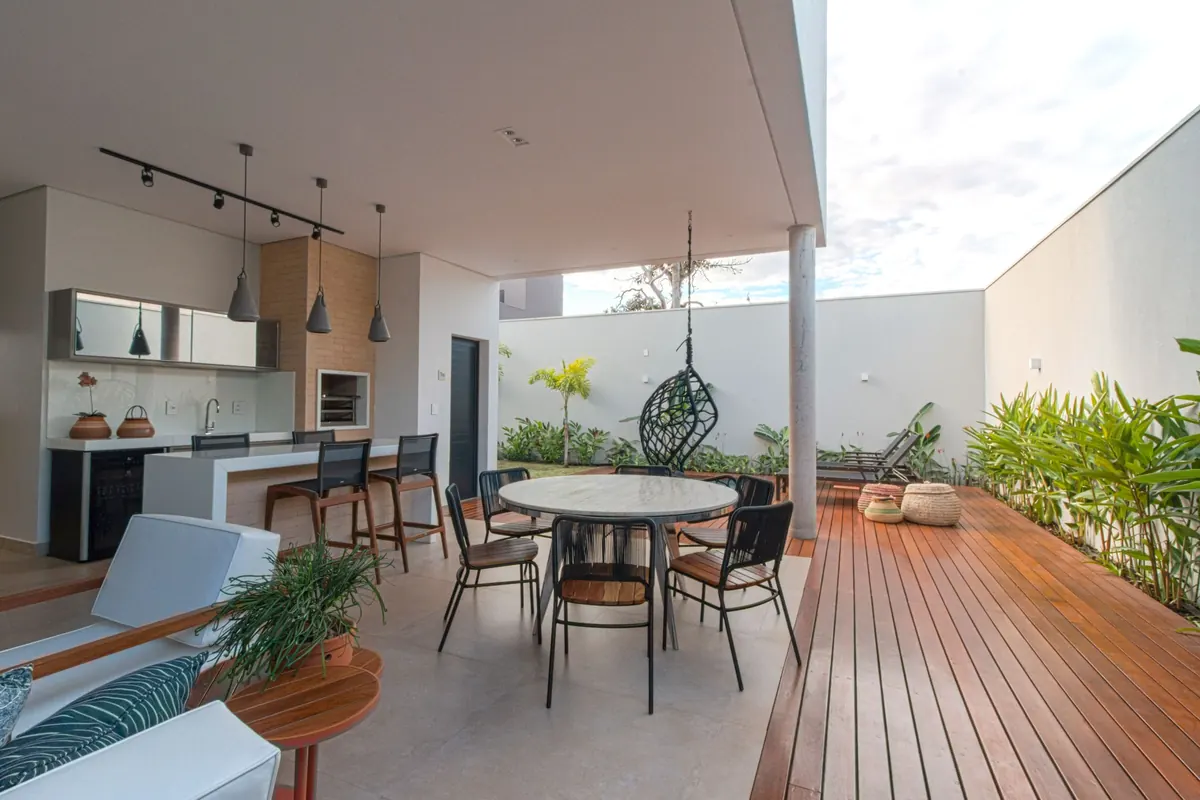 The finished covered terrace: an outdoor kitchen, a round dining table, a hanging chair and hardwood decking.