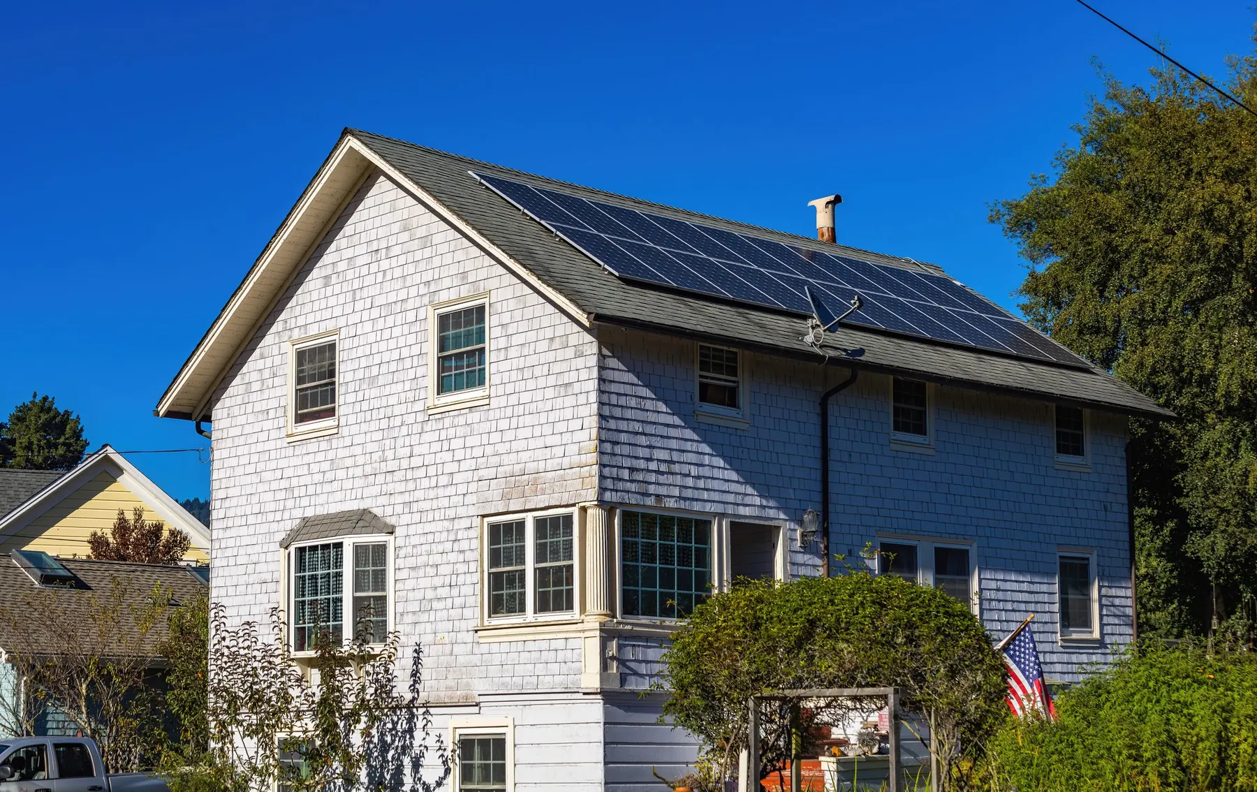 A house with a roof of black solar panels under a clear blue sky